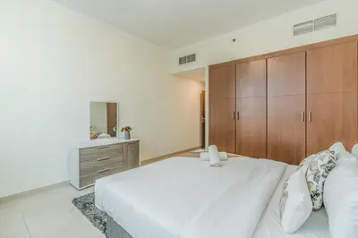 a bedroom with a white bed and wooden cabinets at RH - Best location, 01 BR Spacious, walk to burj in Dubai