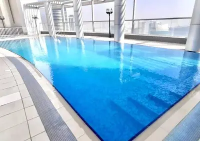 a large swimming pool with blue water in a building at RH - Best location, 01 BR Spacious, walk to burj in Dubai