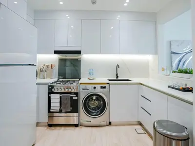 a white kitchen with a washing machine in it at Stylish JVC 1 Bedroom Sanctuary in Dubai