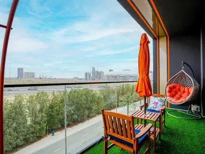 a balcony with an orange umbrella and a chair and a window at Stylish JVC 1 Bedroom Sanctuary in Dubai