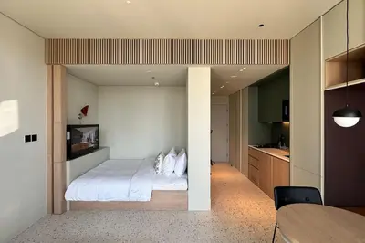 a bedroom with a white bed and a kitchen at Houzzze #4 DesignStudio Burj Khalifa view in Dubai