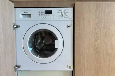 a white washing machine in a wooden cabinet at Houzzze #4 DesignStudio Burj Khalifa view in Dubai