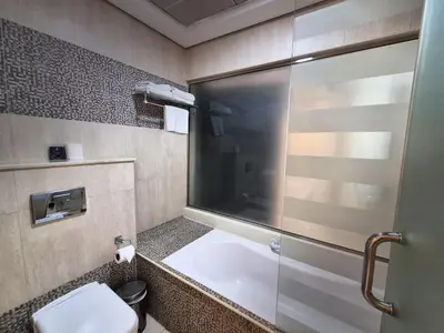 a bathroom with a toilet and a glass shower door at Signature Hotel Al Barsha in Dubai