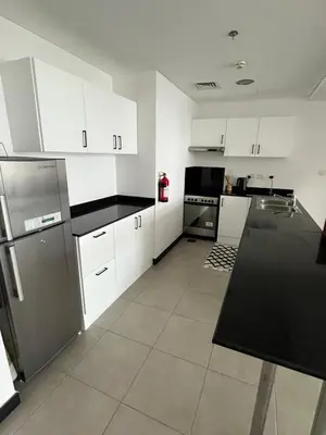 a kitchen with white cabinets and a black counter top at Specious cosy bedroom in Al Sufouh in Dubai