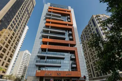 a tall glass building in the middle of two buildings at Silkhaus High Floor 1 BDR with Metro Nearby in Dubai