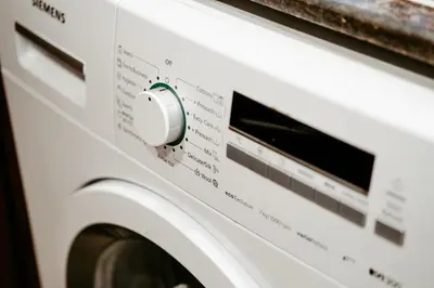a white washing machine with a knob at Dubai Marina Delight: Spacious Retreat for Groups in Dubai
