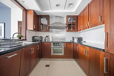 a kitchen with wooden cabinets and stainless steel appliances at Silkhaus Modern 1 BDR With Easy Access to Downtown in Dubai