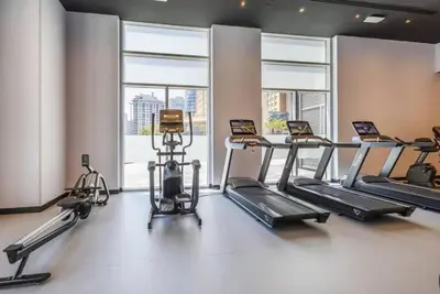 a gym with treadmills and ellipticals in a room with windows at Exclusive 2BR Apartment in Madison Residency - Close to Dubai Internet City Metro Station in Dubai