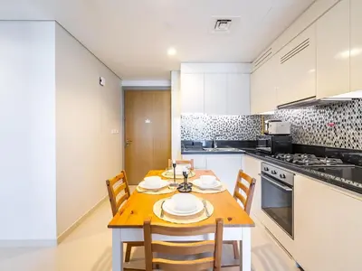 a kitchen with a wooden table and chairs in it at Modern and Cozy Condo With Unobstructed City Views in Dubai