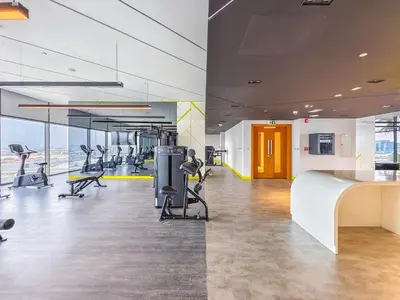 an office with a gym with treadmills and chairs at Modern and Cozy Condo With Unobstructed City Views in Dubai