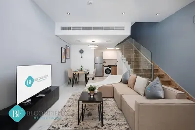a living room with a couch and a staircase at Bloomfields Premium 1br Duplex In Rukan in Dubai