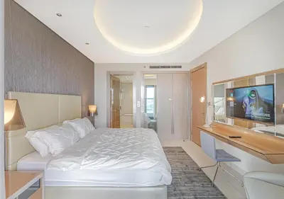 a bedroom with a white bed and a flat screen tv at Savis Homes - Damac Paramount Tower A 1BR Ultimate Luxury and Glam Escape in Dubai