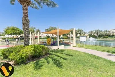 a playground with a slide in a park with a palm tree at Vogue Springs Emirates Living near The Springs Souk, JBR, Marina, Mall of the Emirates, Spacious Villa with Garden and access to Lake and all Amenities in the Community in Dubai