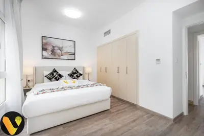 a white bedroom with a large bed and a closet at Vogue Springs Emirates Living near The Springs Souk, JBR, Marina, Mall of the Emirates, Spacious Villa with Garden and access to Lake and all Amenities in the Community in Dubai