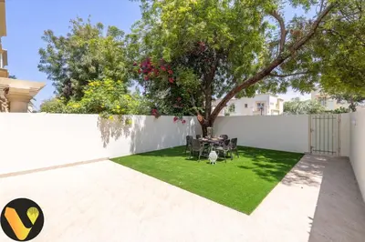 a garden with a table and chairs and a fence at Vogue Springs Emirates Living near The Springs Souk, JBR, Marina, Mall of the Emirates, Spacious Villa with Garden and access to Lake and all Amenities in the Community in Dubai
