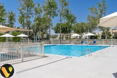 a pool at a resort with chairs and umbrellas at Vogue Springs Emirates Living near The Springs Souk, JBR, Marina, Mall of the Emirates, Spacious Villa with Garden and access to Lake and all Amenities in the Community in Dubai
