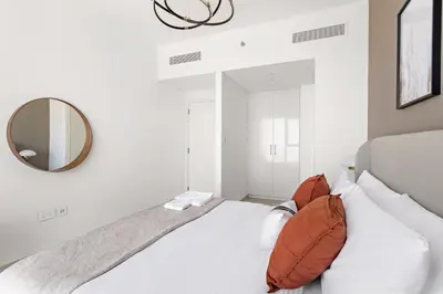 a white bedroom with a large bed and a mirror at Silkhaus High Floor Luxury 1BDR in New Tower in Dubai