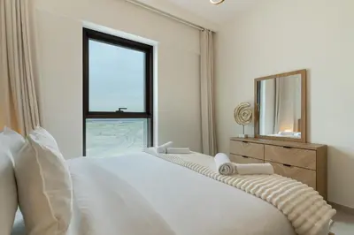 a bedroom with a large white bed and a mirror at Spacious 1-Bedroom in Summer, Lagoon Access Feature - Allsopp&Allsopp in Dubai