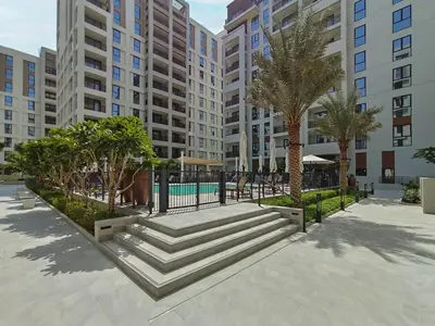 a large apartment complex with a pool and palm trees at Spacious 1-Bedroom in Summer, Lagoon Access Feature - Allsopp&Allsopp in Dubai