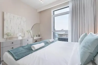 a white bedroom with a large bed and a window at Czechin * Brand New * BeachFront * Palm View * High Floor in Dubai