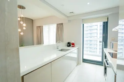 a white kitchen with a sink and a window at Luxe 2BR Haven with Spectacular Burj Khalifa & Dubai Frame Views By ĀYA Boutique in Dubai