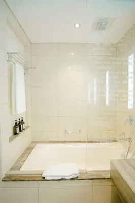 a white bathroom with a tub and a shower at Luxe 2BR Haven with Spectacular Burj Khalifa & Dubai Frame Views By ĀYA Boutique in Dubai