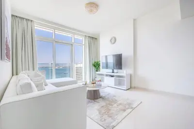 a large white living room with a large window at Elegant 1BR Apartment with Free Beach Access in Dubai