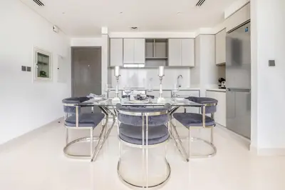 a kitchen with a dining table with blue chairs at Elegant 1BR Apartment with Free Beach Access in Dubai