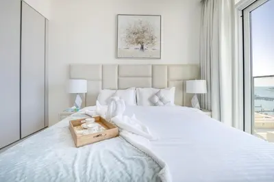 a bedroom with a white bed with a wooden box on it at Elegant 1BR Apartment with Free Beach Access in Dubai