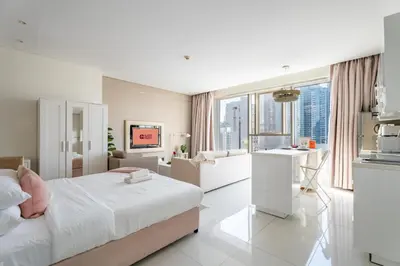 a white bedroom with a bed and a kitchen at GuestReady - Maison Vogue Studio Business Bay in Dubai