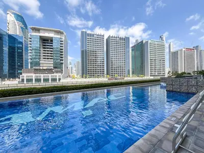 a large swimming pool in front of a city skyline at 1 Bedroom Business Bay Bliss with a Canal View in Dubai
