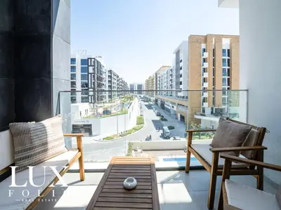 a balcony with two chairs and a view of a city at Chic 1 Bed Meydan Escape with a Pool View in Dubai