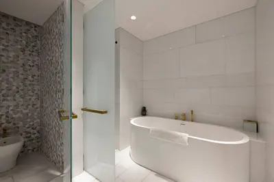 a white bathroom with a tub and a toilet at FIVE Palm Luxury 1BR Apartment with Stunning Views in Dubai
