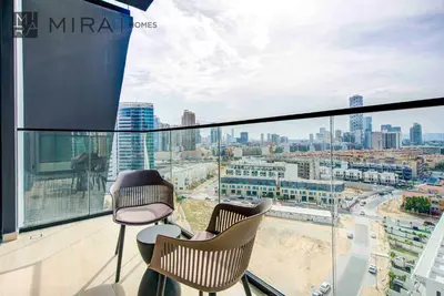 a balcony with two chairs and a view of a city at Mira Holiday Homes - Lovely serviced apartment with pool access in Dubai
