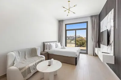 a white room with a bed and a couch and a tv at Chic Studio in new residence with pool sauna gym in Dubai