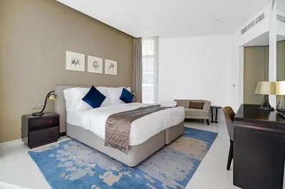 a bedroom with a large bed with a blue rug at Escape24 Stylish 2BR Apartment at Damac Maison Privé, Business Bay with Canal View in Dubai