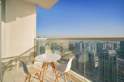 a room with a table and chairs on a balcony at Escape24 Stylish 2BR Apartment at Damac Maison Privé, Business Bay with Canal View in Dubai