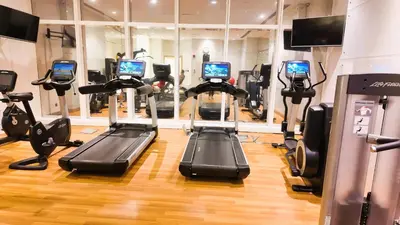 a gym with several tread machines in a room at Damac Heights by Fendi in Dubai