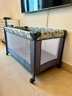 a metal crib in a room with a table at Lux Souk al Bahar Downtown Dubai 1 bedroom flat - Steps to Dubai Mall in Dubai