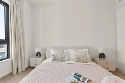a white bedroom with a large bed with two bottles on it at The Smart Concierge - La Rive Port De Lamer in Dubai
