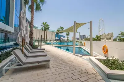 a resort with a pool and palm trees and umbrellas at 1BR Apartment at The Address JBR - Residential in Dubai
