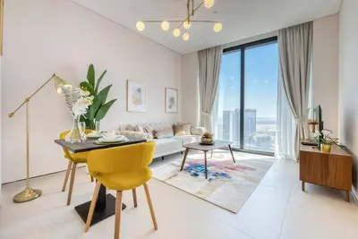 a living room with a table and a yellow chair at 1BR Apartment at The Address JBR - Residential in Dubai