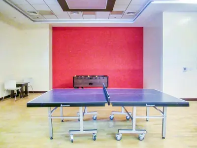a ping pong table in a room with a red wall at The Smart Concierge - Elite residence in Dubai