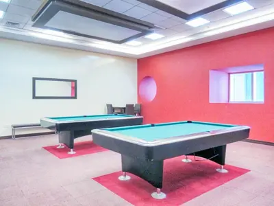 two pool tables in a room with red walls at The Smart Concierge - Elite residence in Dubai