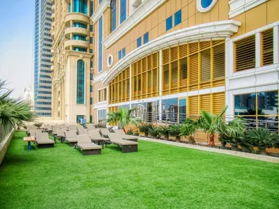 a building with chairs and a lawn in front of it at The Smart Concierge - Elite residence in Dubai