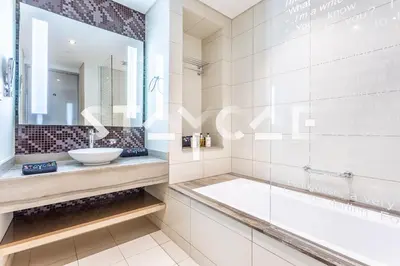 a bathroom with a tub and a sink and a mirror at Staycae Holiday Homes - Damac Towers By Paramount in Dubai