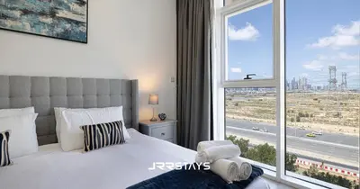 a bedroom with a bed and a large window at Sophisticated Studio JVC - Breathtaking City View in Dubai