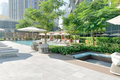 a swimming pool with tables and chairs and trees at 2ndHome - Downtown Views 1 - Downtown Dubai in Dubai