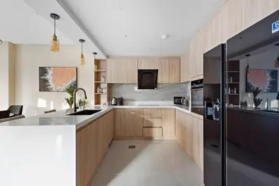 a kitchen with wooden cabinets and a black refrigerator at FIRST CLASS 2BR Incredible Burj Khalifa View in Dubai