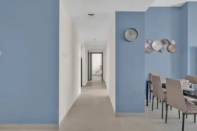 a dining room with blue walls and a table and chairs at Stylish 2BR for 6 with King Beds, Pool, Gym in JVC in Dubai